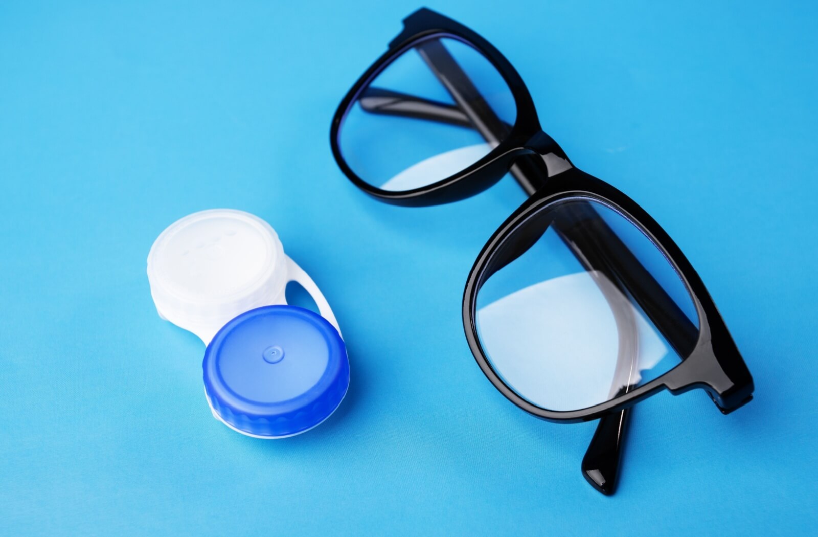 Contact Lens and Eyeglass are displaying on the table with a blue background.
