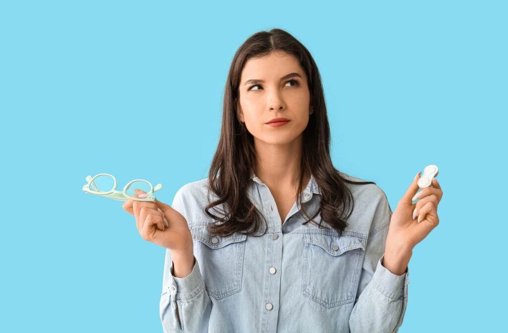 A person is holding eyeglasses and contact lens container in her hands.